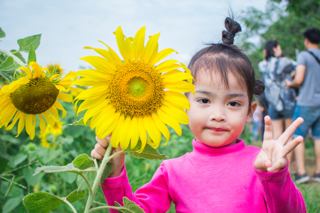 happy little girl smile with sunflower garden. soft focus.の写真素材