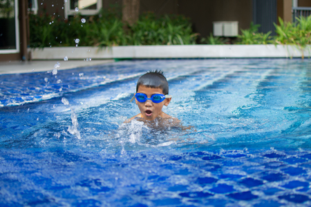 cute little boy feel happy play and swimming at swimming pool , sunny day and soft focus.の写真素材