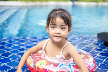 cute little girl feel happy play and swimming at swimming pool , sunny day and soft focus.の写真素材
