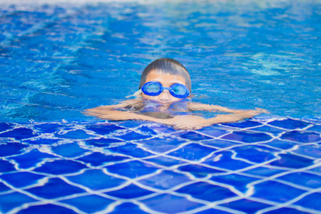 cute little boy feel happy play and swimming at swimming pool , sunny day and soft focus.