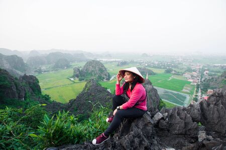 happy woman stand on peak of mountain at Mua Cave, Ninh Binh, Vietnam at evening, subject is blurred, low key and noise.の写真素材