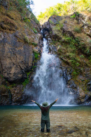 waman stand in front of beautiful waterfall name's Jok ka din in Kanchanaburi province, Thailand. subject is blurred.の写真素材
