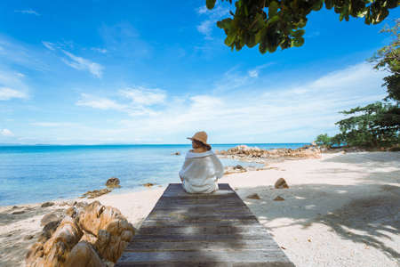 happy woman sitting on wood bridge with view of the sea, soft focus with noiseの写真素材