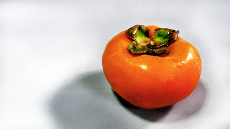 Ripe Persimmon on Gray Background with Empty Space on the Leftの写真素材