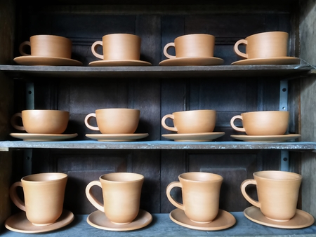 Retro Brown Clay Cups for Hot Coffee or Tea in Row on Shelfの写真素材