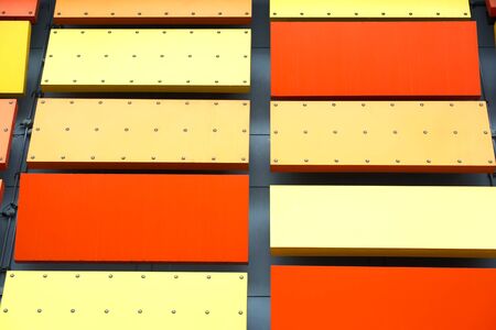 Vivid Orange and Yellow Decorative Metal Plates on the Wallの写真素材