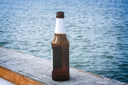 Empty Bottle of Beer On the Bridge By the Seaの写真素材