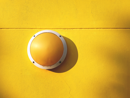 Round Yellow Light Luminaire Fixture on Vivid Yellow Wall Backgroundの写真素材