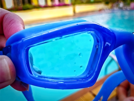 Close-up Shot of Blue Swimming Goggles on Blurred Swimming Pool Backgroundの写真素材