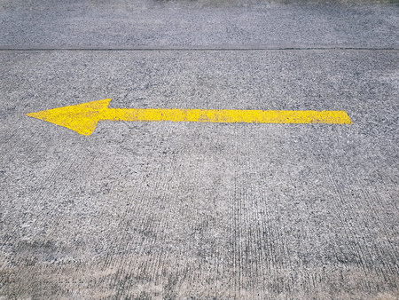Yellow Painted Traffic Arrow Sign on Street Pointing to the Leftの写真素材