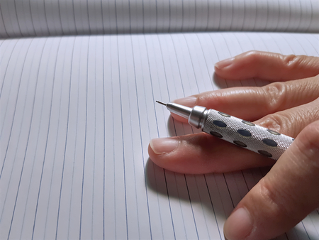 Close-up Hand Holding Mechanical Pencil on Notebook Paperの写真素材