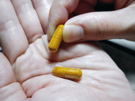 Close-up Shot of Taking Medication Capsules from Palm of Handの写真素材