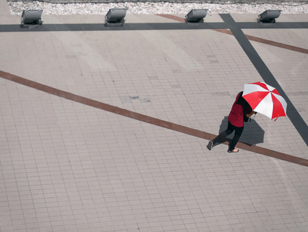 High Angle View of A Woman Walking Holding Red and White Umbrellaの写真素材