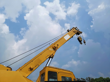 Low Angle View of Telescopic Boom with Hoist of Yellow Crane at Construction Site Against Cloudy Skyの写真素材