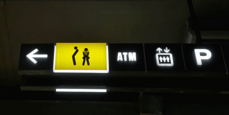 Low Angle View of Yellow Illuminated Toilet Sign and Other Symbolsの写真素材