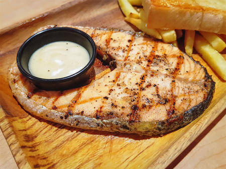 Grilled Salmon Steak with Dipping Sauce and  Fries on Wooden Plateの写真素材