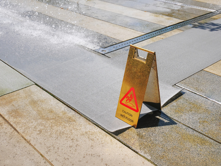 Golden Caution Wet Floor Warning Stand Near Dripping Water at the Park