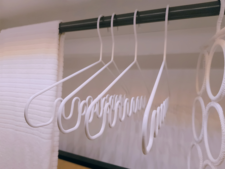 White Curvy Cloth Hangers and Towel Inside the Wardrobeの写真素材