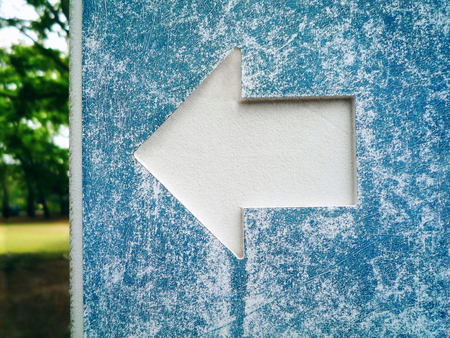 Close-up White Arrow Symbol on Old Cyan Sign Post