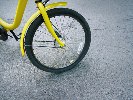 Close-up Front Wheel of Yellow Bicycle on Asphalt Road
