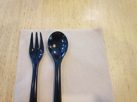 Black Spoon and Fork with Tissue Paper on Wooden Table for Dessertの写真素材