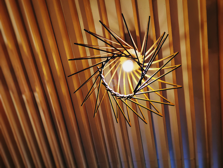 Low Angle View of Hanging Illuminated Light Bulb on Wooden Planks Ceilingの写真素材