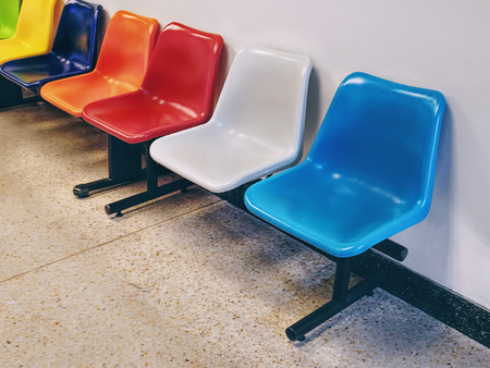 Row of Colorful Plastic Chairs Against White Wallの写真素材