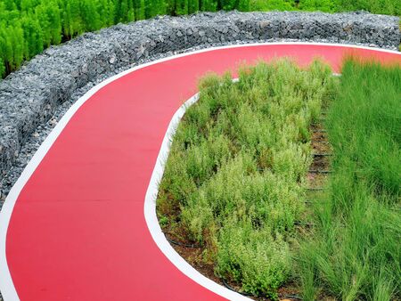 Empty Red Single Lane Road for Biking Through Plants and Bushes in the Parkの写真素材