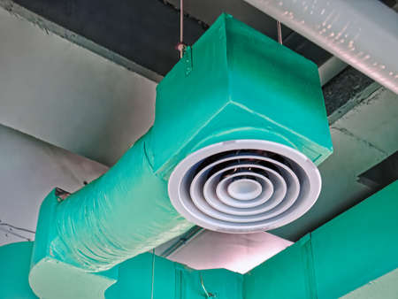 Low Angle View of Green Insulated Air Conditioning Duct with Round Grille Diffuserの写真素材