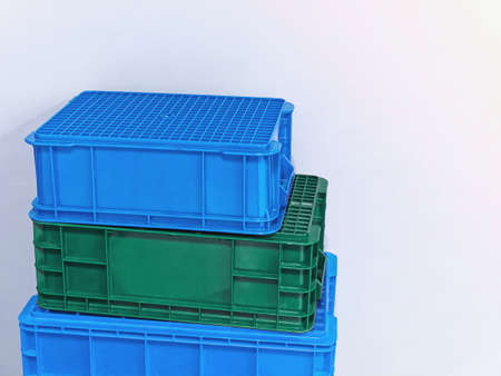 Stacked Green and Blue Plastic Baskets Against White Wall