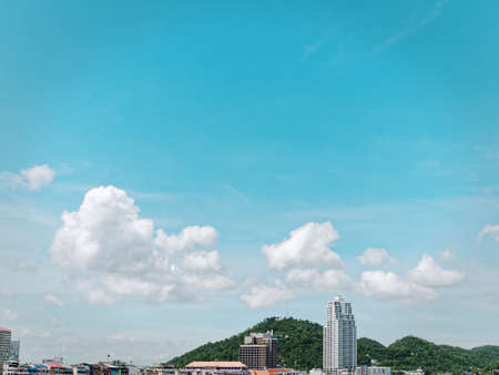 Tranquil Scenery of Cityscape with Green Mountain Hill and Cloudy Blue Skyの写真素材