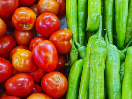 Close-up Pile of Fresh Red Tomatoes and Green Chili Peppers for Saleの写真素材