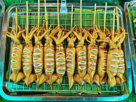 Pile of Squid Skewers on Banana Leaf Trayの写真素材