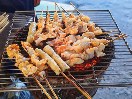 Hot Grilled Squid Skewers on Metal Grate Over Charcoal Stoveの写真素材