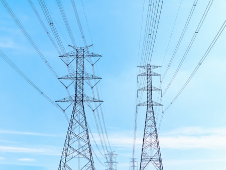 Low Angle View of High Voltage Electrical Transmission Towers and Cables Against Blue Skyの写真素材