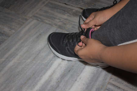 hands tying shoelaces while wearing sport shoe for outdoor sports or gym. colseup shot showing...