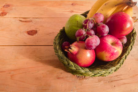 assorted colorful fruits kept in a basket. apple, pomegranate, grape, berry, banana, guava kept together. close up shot. copy space background.の写真素材