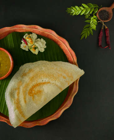 traditional south indian food masala dosa, sambar and coconut chutney served on clay plate and...
