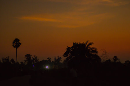 silhouette landscape during dusk or dawn with black trees and houses. sky in red and yellow.の写真素材