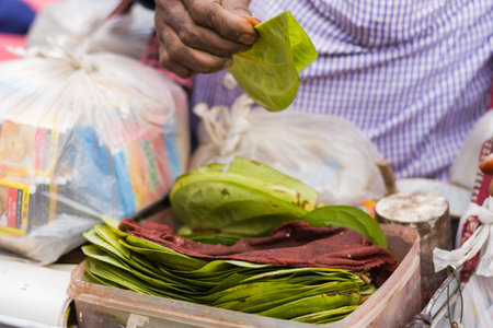 Betel leaves being sold in roadside shop of India. Very popular street food in india.hand holding green betel leaves for stuffing with with various condiments and serving to customers.の写真素材