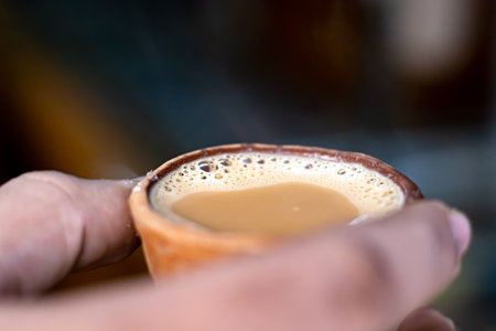 Hot milk tea or chai in traditional kulhad or clay pot or earthen cup held by hand. This is very popular drink in india.の写真素材
