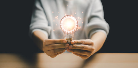 Woman holding a light bulb Inside the lamp, there is a cog logo that is emitting light. are...