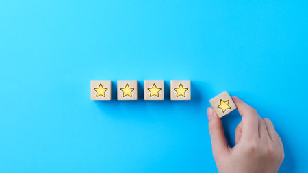 Customer review satisfaction feedback survey concept. Hand put wooden cube block with yellow star icon on blue background. Client questionnaire, Service rating user, Business evaluation, 5, Five star,の写真素材