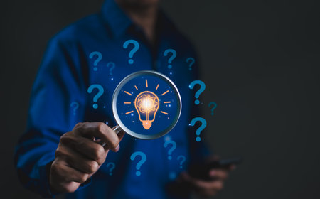 The concept of using creative thinking to help solve problem. Innovation patent, Find solution, think idea, Businessman holding magnifying glass icon with many idea light bulb and question marks.の写真素材