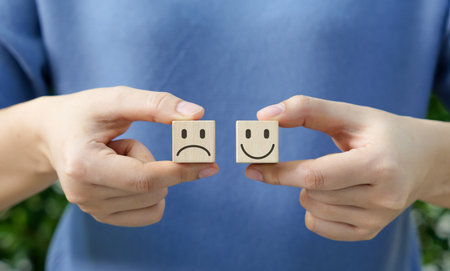 Choosing emotions with wooden block. Holding wooden cubes with happy and sad faces, concept of choosing your attitude or emotion. Customer review satisfaction feedback survey, Mental health assessmentの写真素材