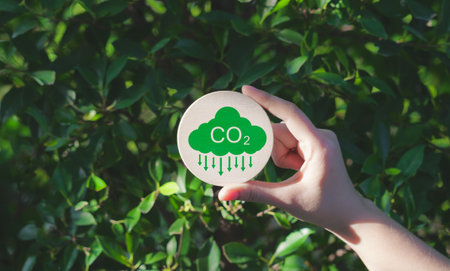 Reduce CO2 emission concept. A hand holds a green CO2 emissions symbol, representing carbon footprint awareness, net zero, and carbon neutrality. Climate change, Global warming, Greenhouse gas,の写真素材