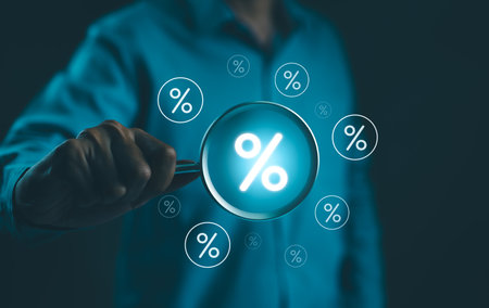 Interest Rate and Dividend Concept. Businessman holds a magnifying glass with virtual percentage symbols surrounding it, representing interest rate and dividend concepts in financial analysis.の写真素材