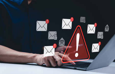 Email security warning notification concept. A person using laptop with email security alert icons and warning notifications, indicating cybersecurity threats such as spam, viruses, junk mail, scams,の写真素材