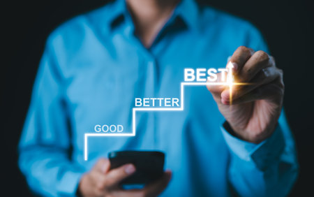 Progress from Good to Better to Best Concept. Businessman marks steps labeled "Good," "Better," and "Best", continuous improvement, goal achievement, and excellence in personal or professional growth.の写真素材