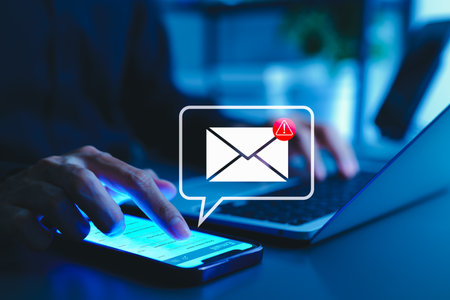 Email security warning notification concept. A person using a smartphone with email security alert icons and warning notifications, indicating cybersecurity threats, spam, virus, junk mail, and scams.の写真素材